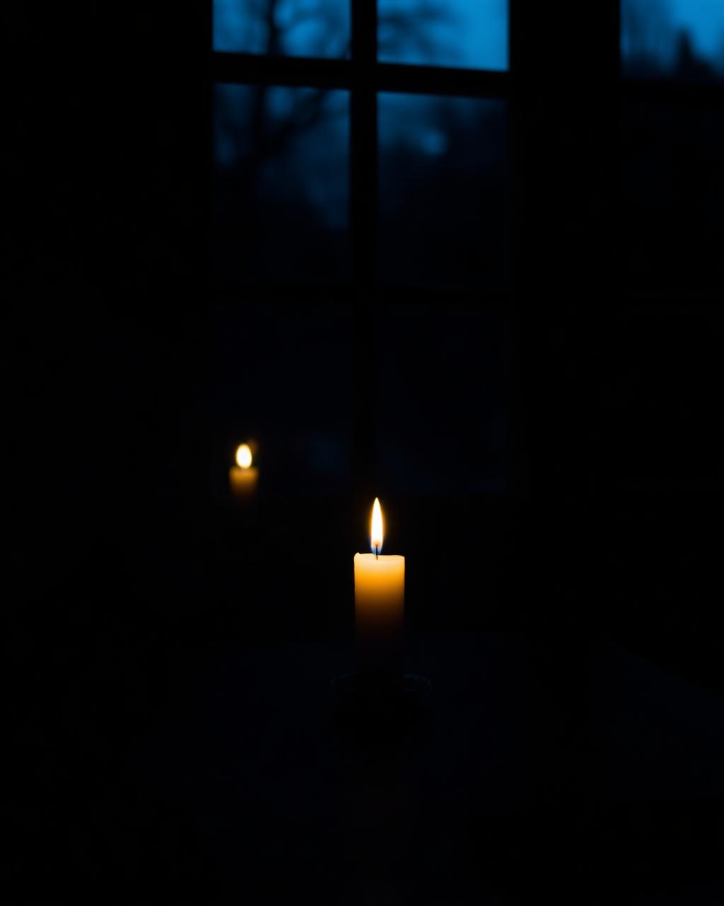 A single candle by a window at twilight